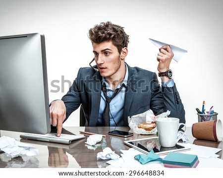 Guy with paper plane in his hand typing on a computer keyboard / modern office man at working place, sloth and laziness concept