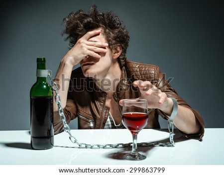 Young man drinking red wine and feeling despair / photo of youth addicted to alcohol, alcoholism concept, social problem