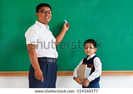 A student with teacher near blackboard in the classroom / photo of teen and teacher school Chinese boy, creative concept with Back to school theme
