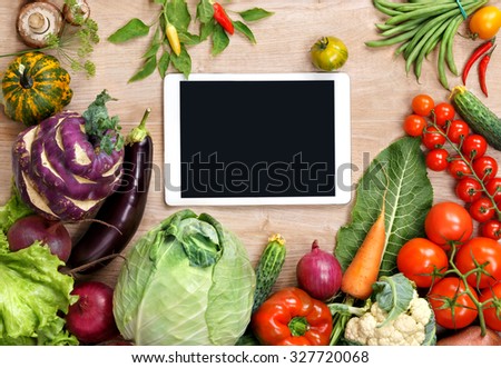 Fresh organic vegetables on a wooden background and digital touch screen tablet. Fresh vegetables background. Diet. Dieting. Space for your text.