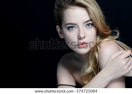 Beautiful sensual blonde girl. Close-up of an attractive girl of European appearance on dark background.