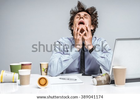 OMG! Frustrated man sitting desperate over paper work at desk. Negative emotion facial expression feeling