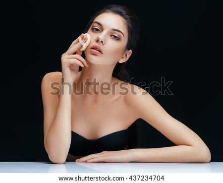 Young woman applying powder on her face with powder puff. Skin care concept