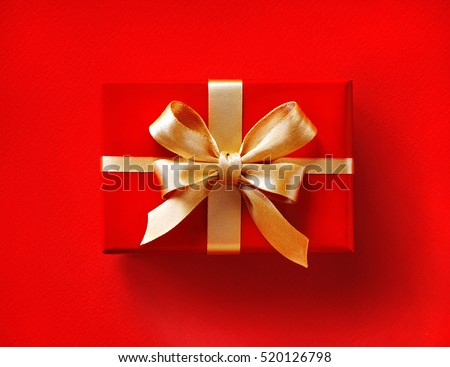 Gift box with golden ribbon on red background. Close up. Top view. High resolution product
