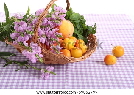 Beautiful basket with wild flowers and fruits at the violet tablecloth