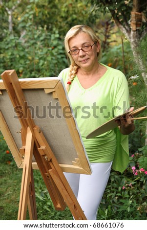 Smiling aged woman painting in her garden.
