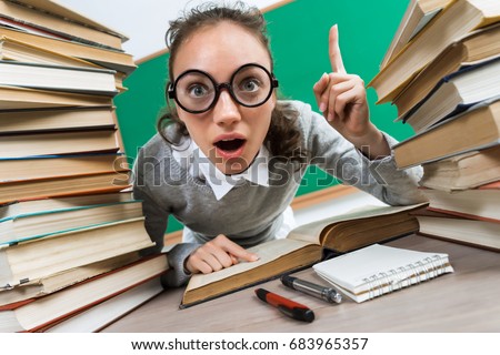 Student having good idea, pointing finger up. Photo of astonished young girl wearing glasses around books. Education concept