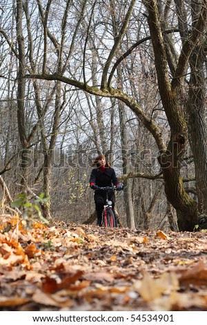 Young female bicycle rider in autumn park