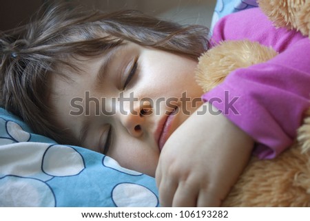 sleeping child in her bed with teddy bear
