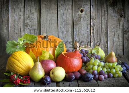 Vegetables pumpkins and fruits in autumn halloween season still life on vintage wooden boards