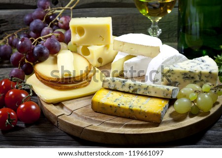 Cheese many various types on cutting board with wine vintage still life