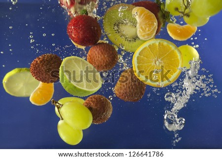 Fruits splash in water with bubbles against blue background