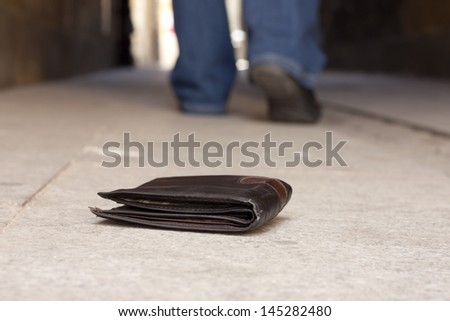 Lost wallet on the street and legs of the walking man concept
