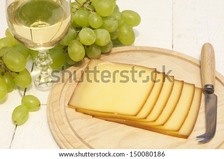 Cheese and glass of wine closeup on cutting board