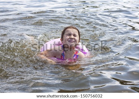 Child learns to swim in the lake with lifebuoy