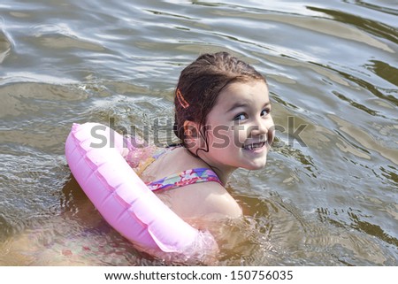 Child learns to swim in the lake with lifebuoy