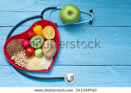 Food on heart plate with stethoscope cardiology concept on blue boards