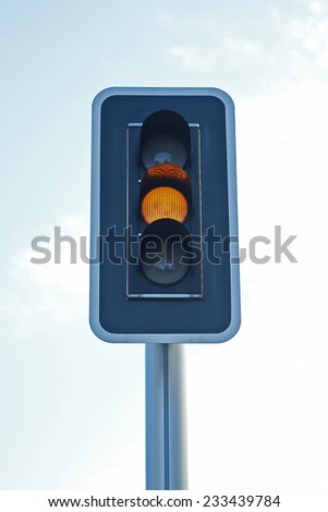 Closeup of a orange traffic light with blue skies in the background