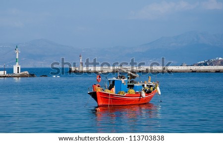 Red fishing boat moored at sea. Mykonos Greece.