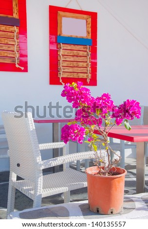 Restaurant on the narrow street of the island in Greece with  tables and shrubs flowers