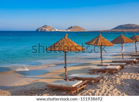 The sandy beach near the blue sea with sun beds and umbrellas. Mykonos