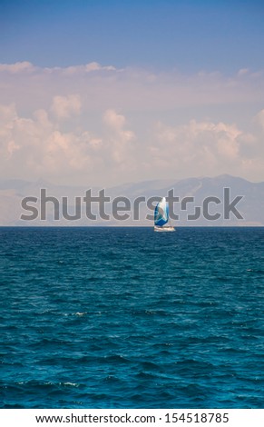 Small yacht in the blue sea off the coast with beautiful clouds