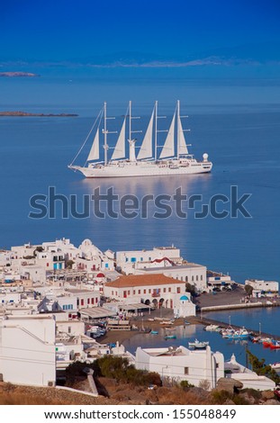 Top view of the town and port of Mykonos Island and a sailing ship in the blue sea ...