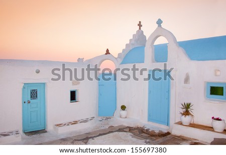 Traditional white-blue Greek family church near the sea at sunset
