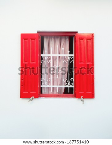 Beautiful red window with bars and curtain on the white wall. Background.