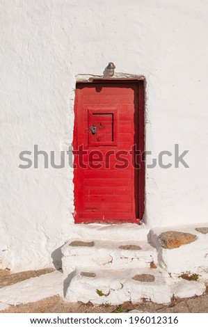 Red wooden door of old windmill at sun. Mykonos. Greece.