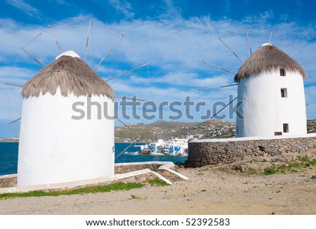 Two windmills of Mykonos on the background of Little Venice. White buildings, blue sky and the sea - the national colors of Greece