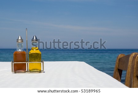 bottles of olive oil and vinegar on the table with a tablecloth near the sea