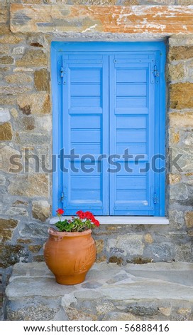 Window with blue shutters in a rustic house with a flower in a clay pot