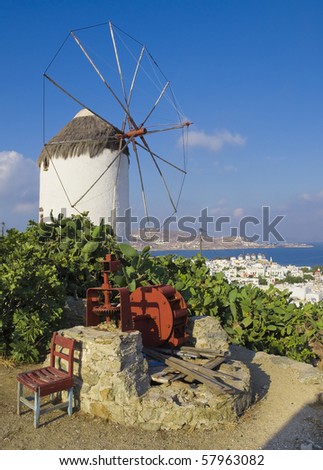 windmill above the town of Mykonos and a stone well with the engine. Top view of the town of Mykonos in Greece