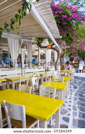 Restaurant on the narrow street of the island in Greece with colored tables