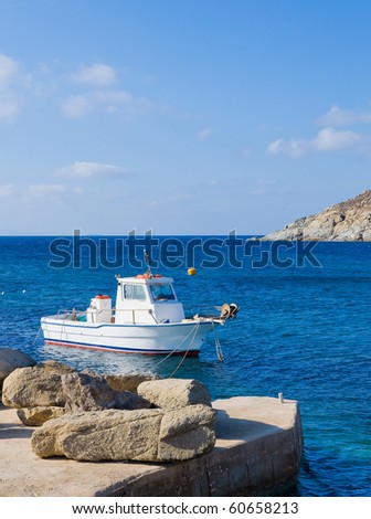 Greek fishing boat in the sea near the pier with a stone ...