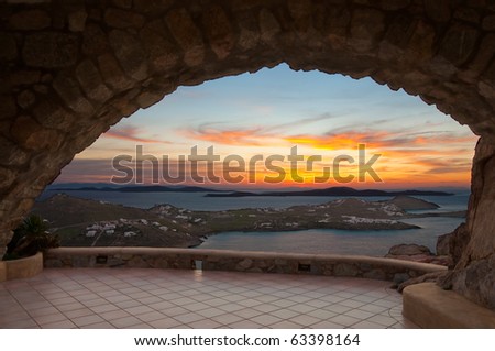 bright orange sunset on the sea islands, which can be seen through the arch of the house in Mykonos