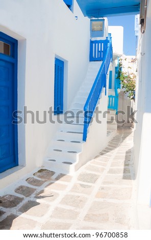 Narrow streets with white houses, ladders and blue windows and balconies on the islands of the Mediterranean. Mykonos. Greece.