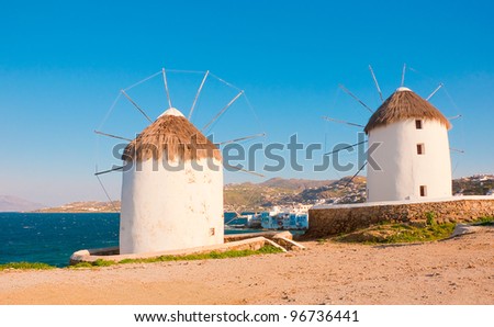 Two windmills of Mykonos on the background of Little Venice. White buildings, blue sky and the sea - the national colors of Greece
