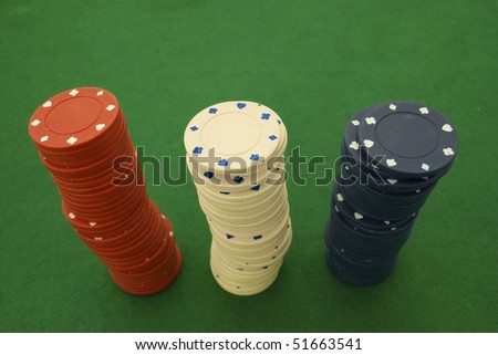 Stacks of red, white, and blue poker chips on a green poker table background