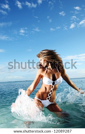 Beautiful swimsuit model splashing water on vacation