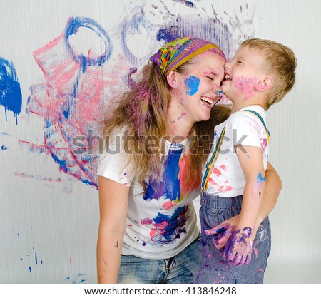 Mother and son paint the walls/ drawing on wall. Child himself dirty in the paint and looks into the camera. Child has fun and stain the wall. Children\'s creativity. Art for baby.