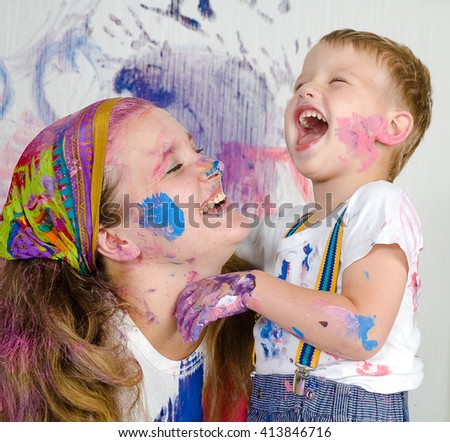 Mother and son paint the walls. Child himself dirty in the paint and looks into the camera. Child has fun and stain the wall. Children\'s creativity. Art for baby.