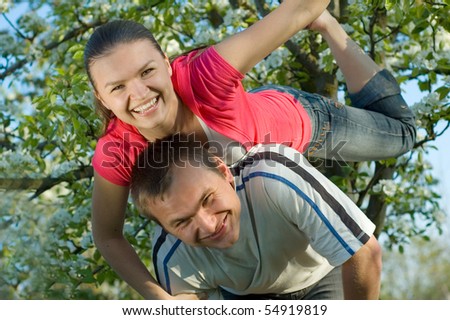 Young couple playing in a flowering garden and looking at the camera