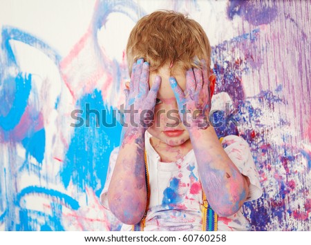 the boy himself dirty in the paint and covers his face with his hands