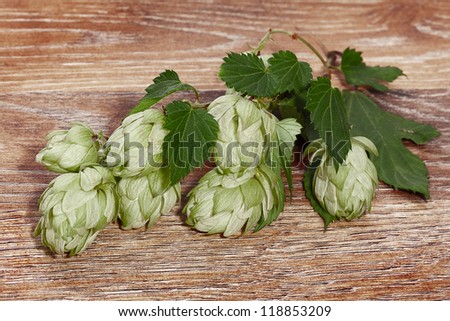 Hop cones with leaves on a wooden surface