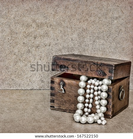 Old wooden chest with jewels and pearls on vintage background