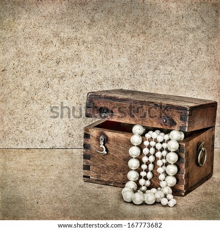 Old wooden chest with jewels and pearls on vintage background