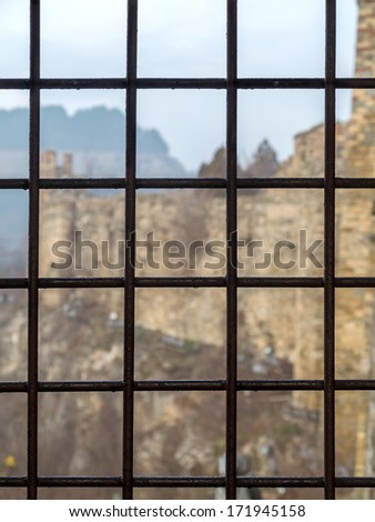 Brick fortress seen through the prison window with metal bars