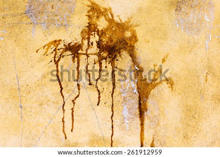 Creative background yellow concrete wall with cracks and scratches doused with brown paint splashes and drips. For creative unusual vintage design